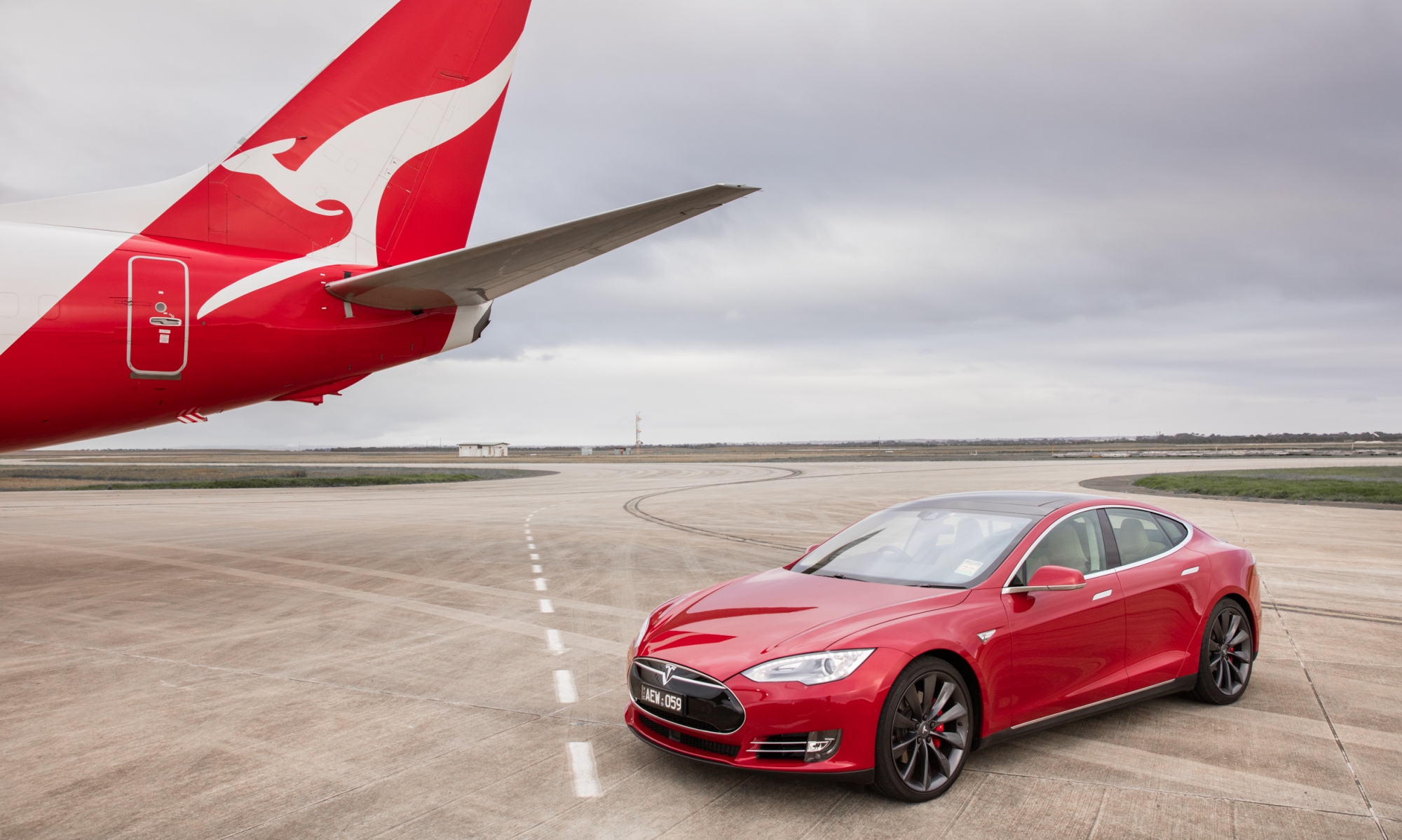 a qantas plane races a tesla in cross promotion to push sustainability